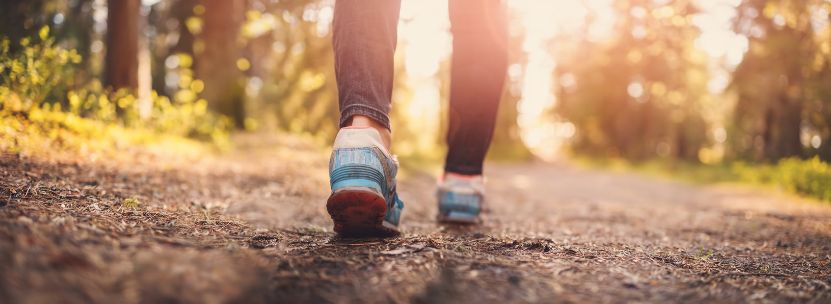 A womans feet walking along a forest path