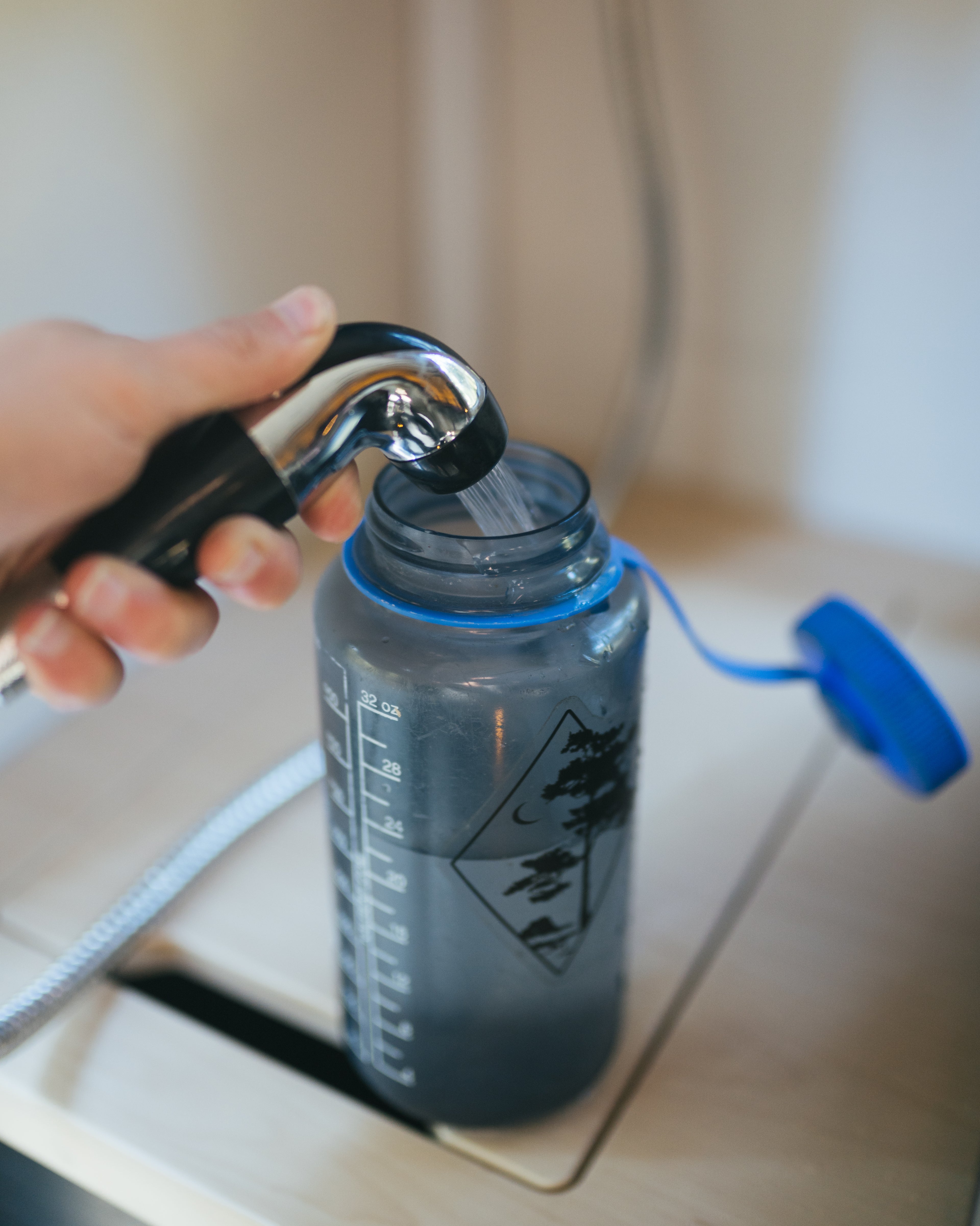 Person using a water filter system on a bottle with a blurred background