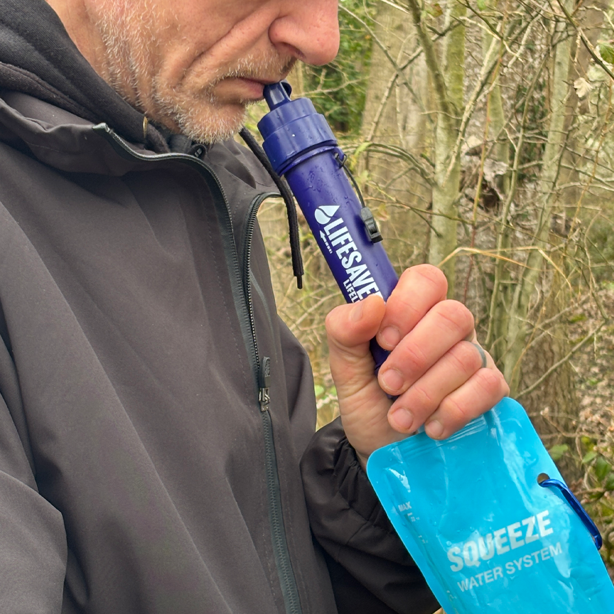 Person using a LifeStraw water filter in a natural setting