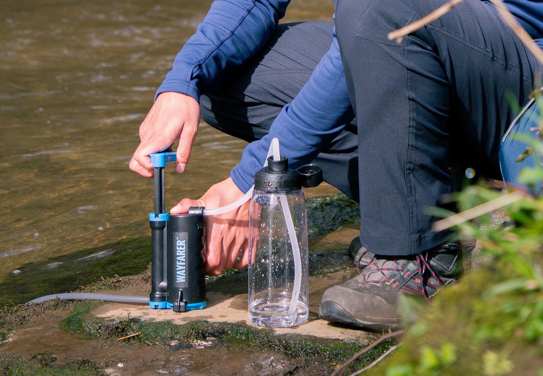 Person using a LifeSaver Wayfarer water filter to purify water from a natural source